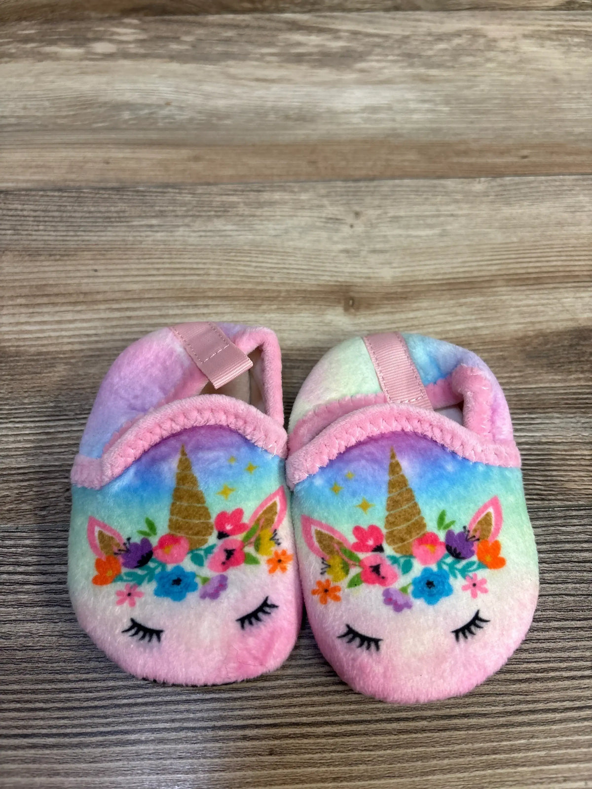 Side view of pair of pink plush unicorn toddler slippers (size 5C) showing plush texture and unicorn face detail on white background