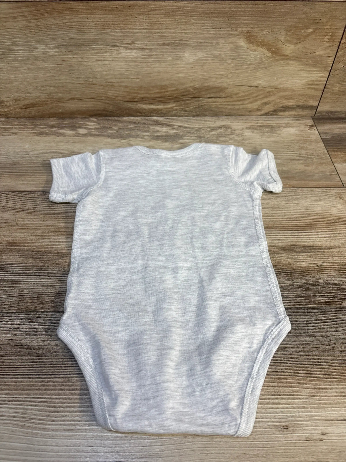 Back view of grey Rabbit Skins baby bodysuit size 12 months showing short sleeves and plain back laid flat on wood background
