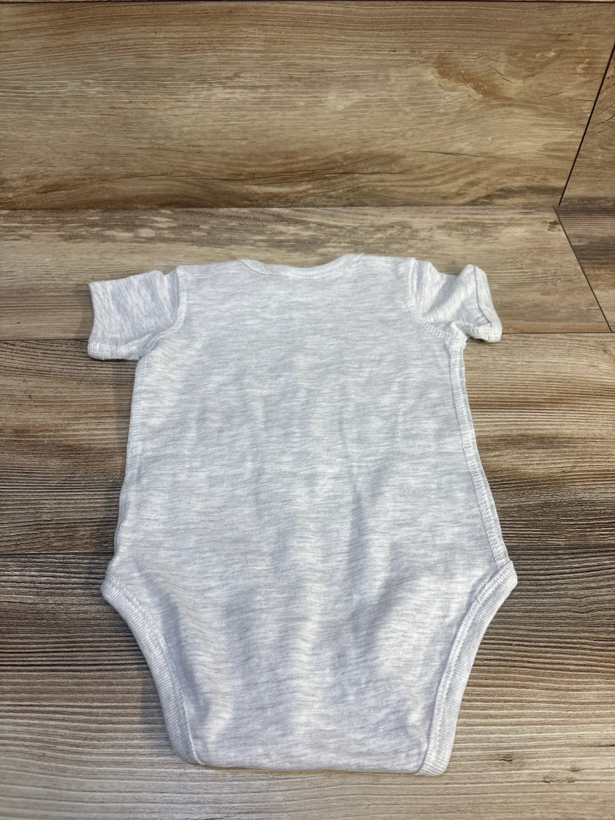 Back view of grey Rabbit Skins baby bodysuit size 12 months showing short sleeves and plain back laid flat on wood background