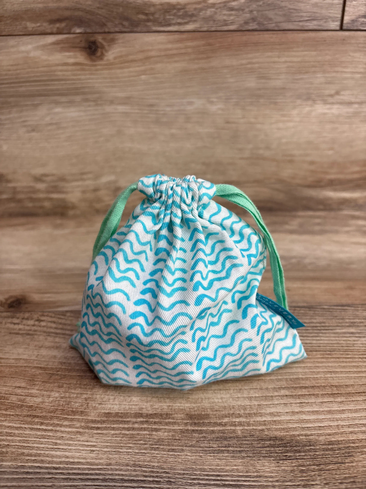 Drawstring fabric bag with blue wavy pattern, kids accessory, on wooden background