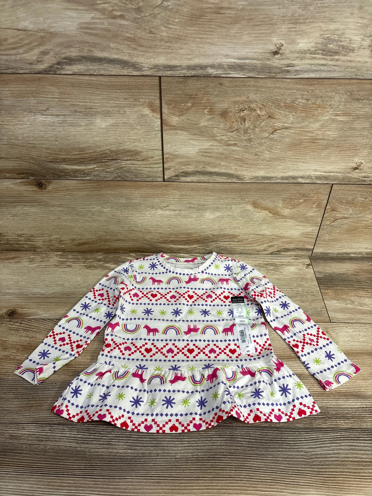 Long-sleeve toddler dress with unicorn, rainbow, heart, and star pattern on wooden floor