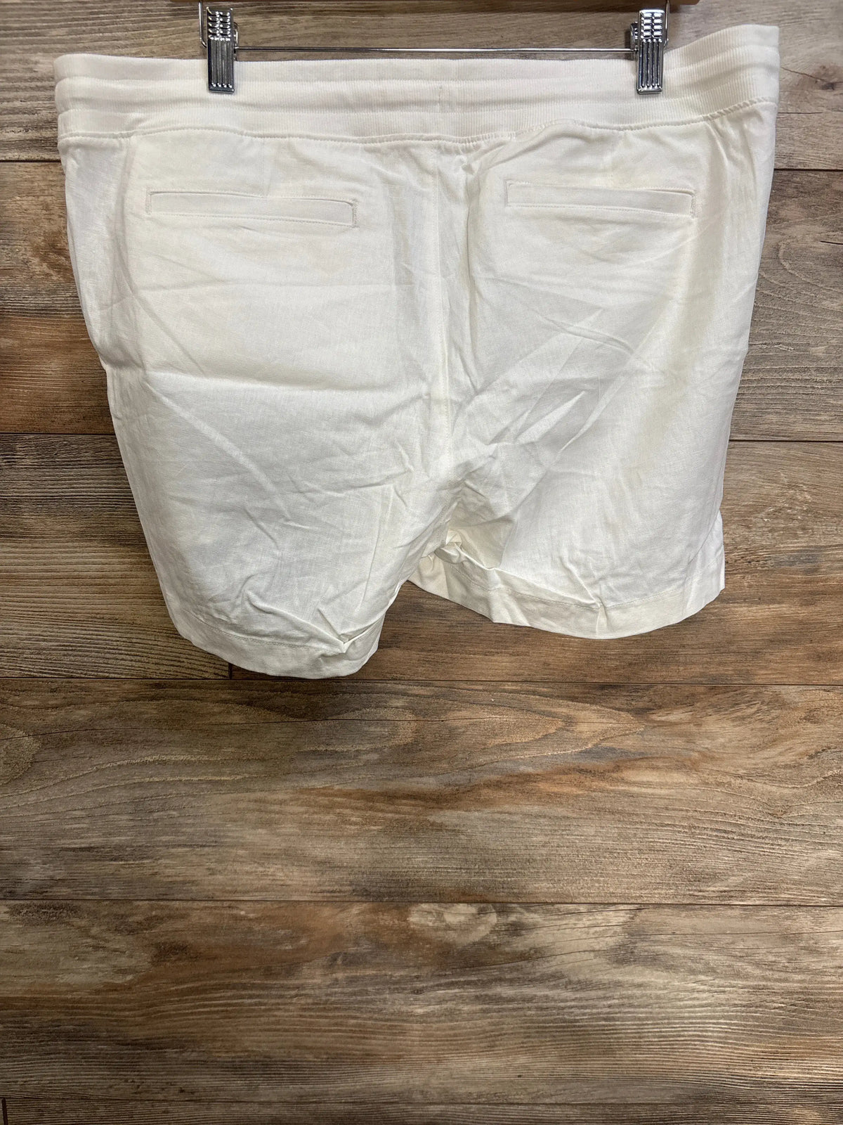 Back view of NWOT Gap maternity linen-blend shorts showcasing two back welt pockets and elasticized waist against a wood background