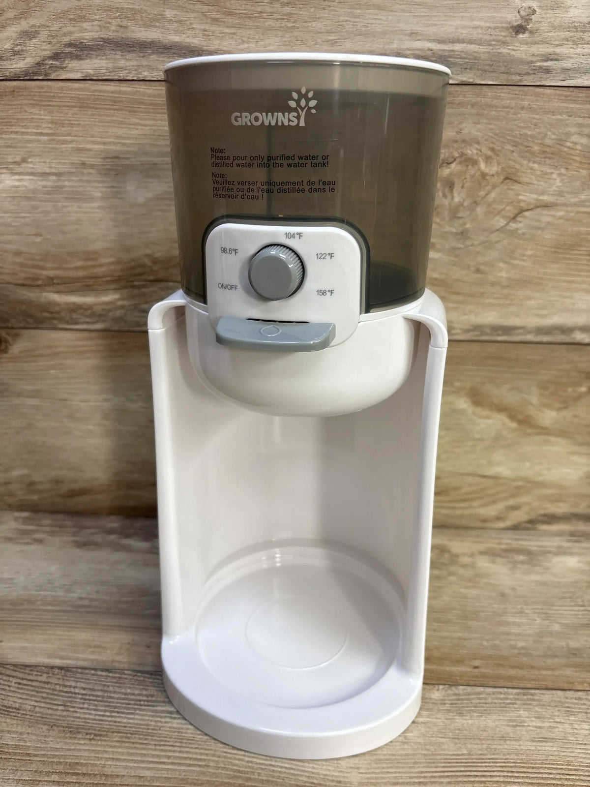Front view of GROWNSY instant baby bottle warmer showing temperature dial and dispenser spout against wood background