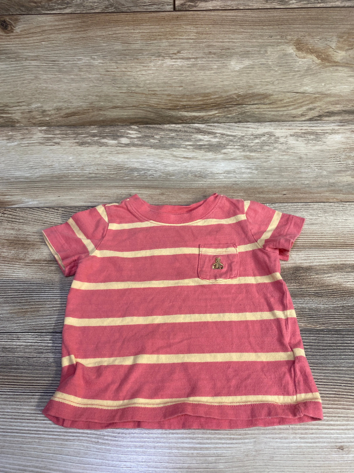Flat lay of Baby Gap red and cream striped pocket shirt, size 12-18 months, showing chest pocket on wood background