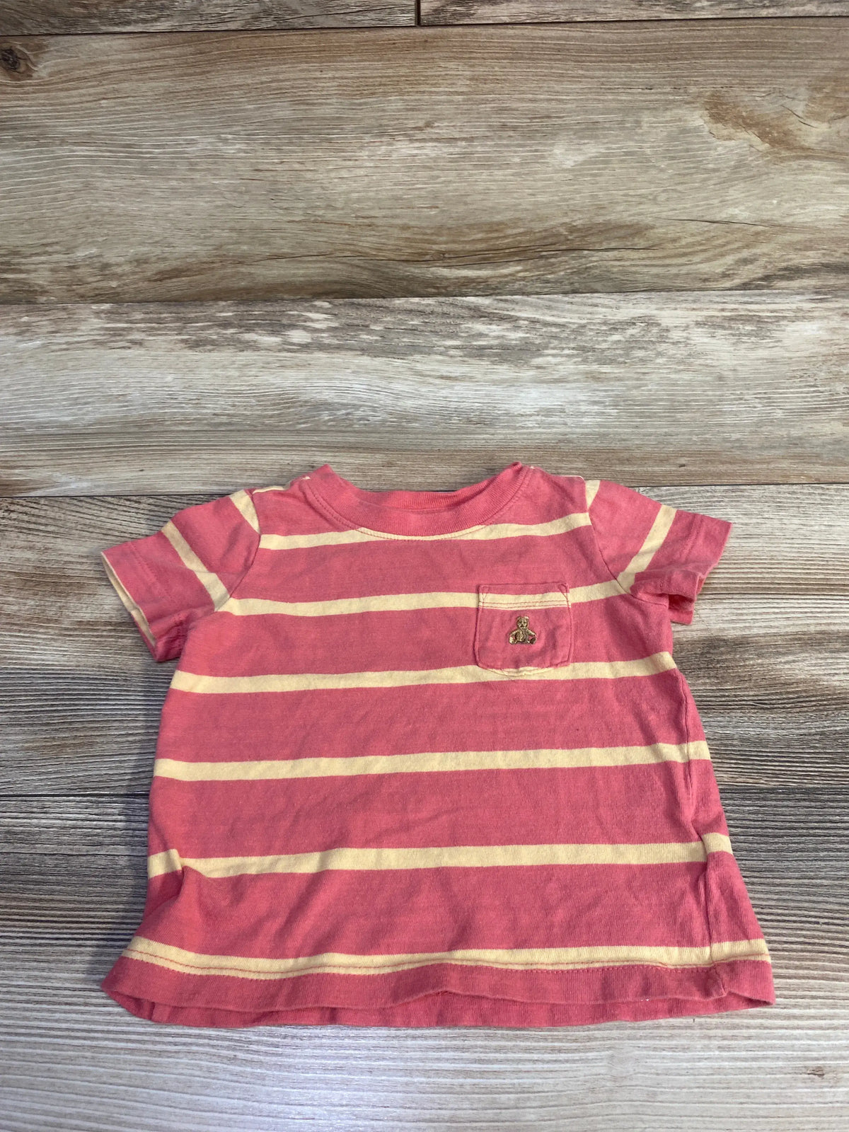 Flat lay of Baby Gap red and cream striped pocket shirt, size 12-18 months, showing chest pocket on wood background