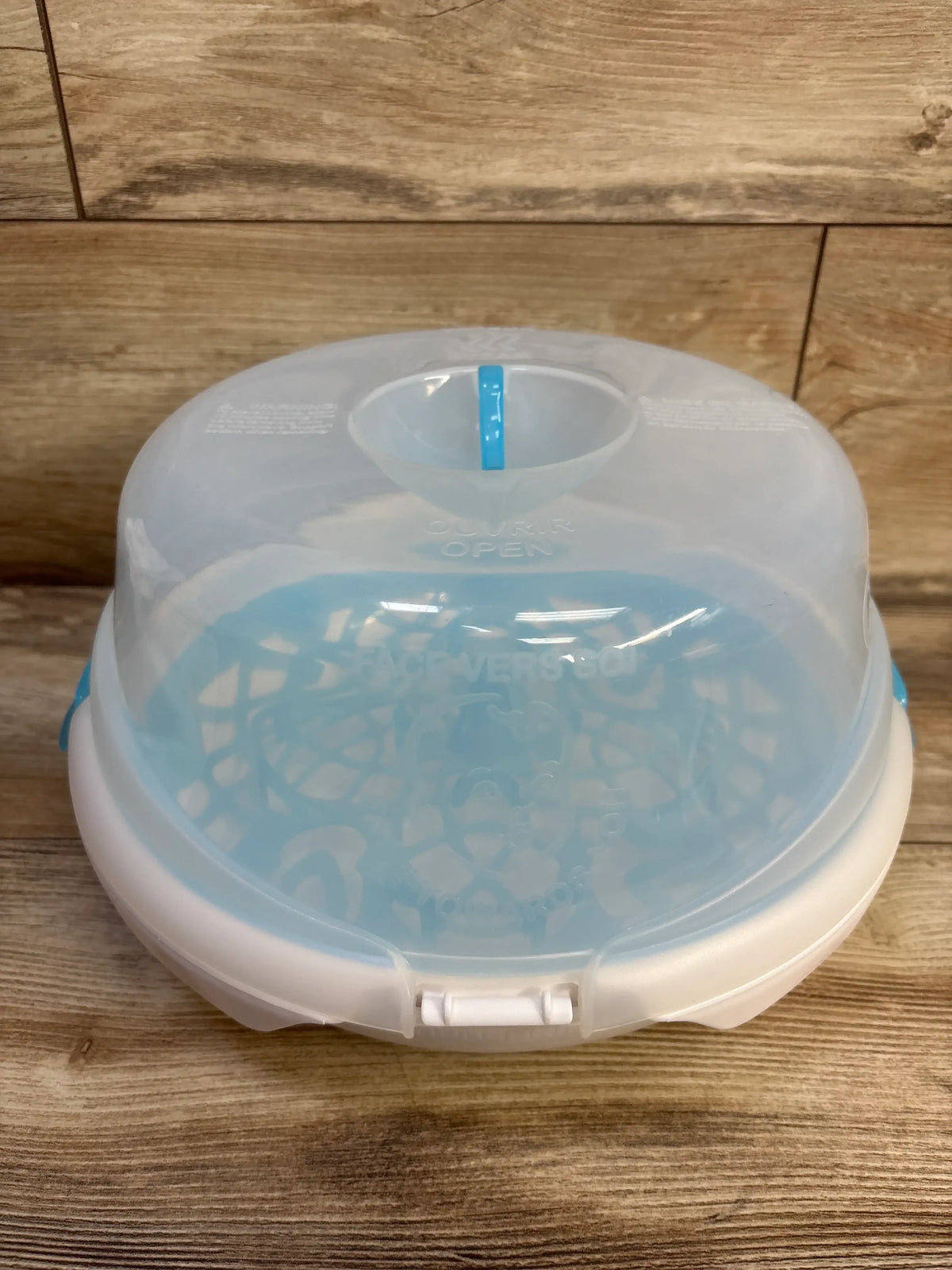 Front view of Munchkin Steam Guard microwave bottle sterilizer with translucent lid and blue interior on a wood surface