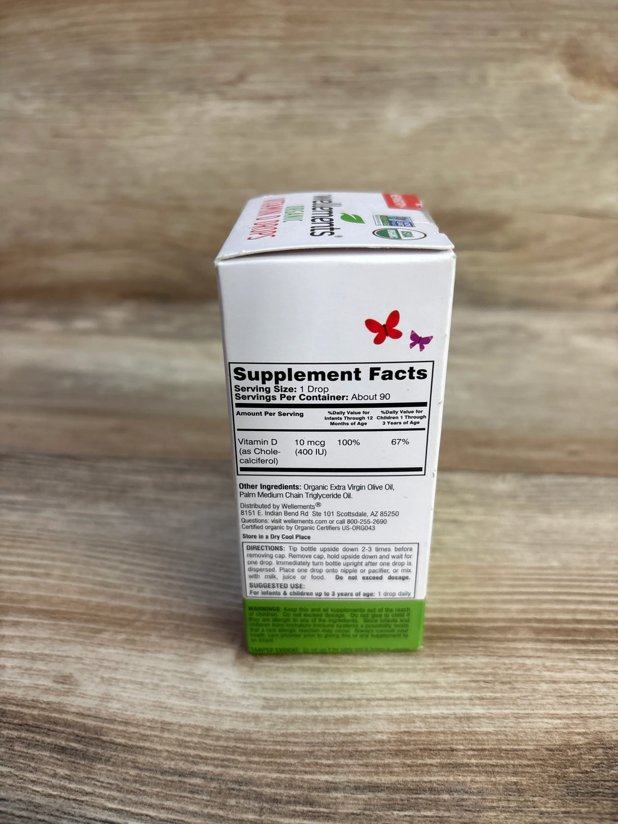 Wellments vitamin D3 drops supplement box with nutrition facts on wood background