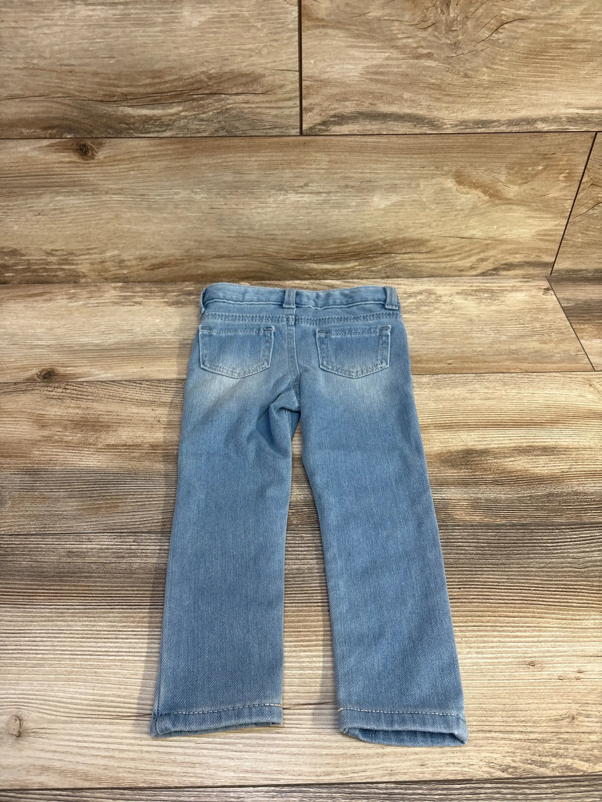 Rear view of Cat & Jack blue jeggings in size 2T showcasing two back pockets and adjustable waist on a wood-patterned floor