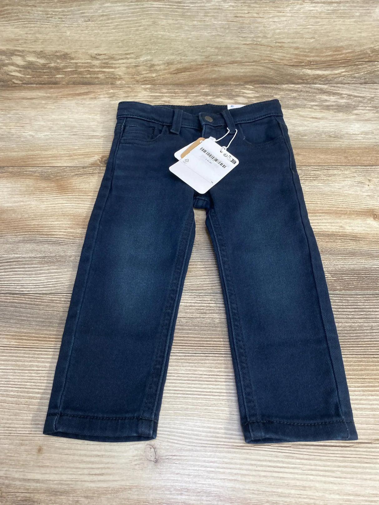 Flat lay of navy Mayoral slim-fit toddler pants size 12 months showing front pockets and attached tags on wooden background