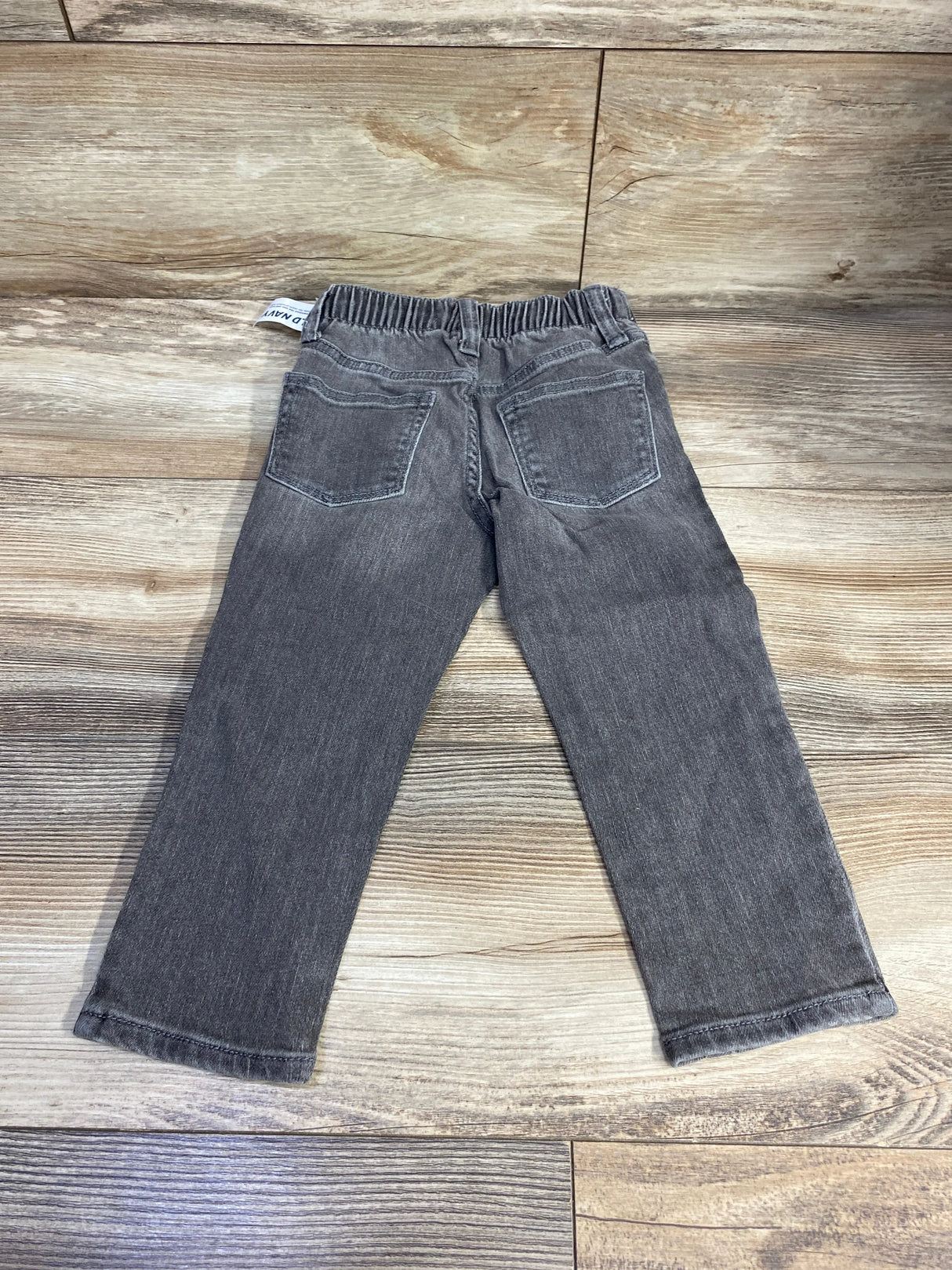 Gray toddler jeans with back pockets and elastic waistband on wood floor
