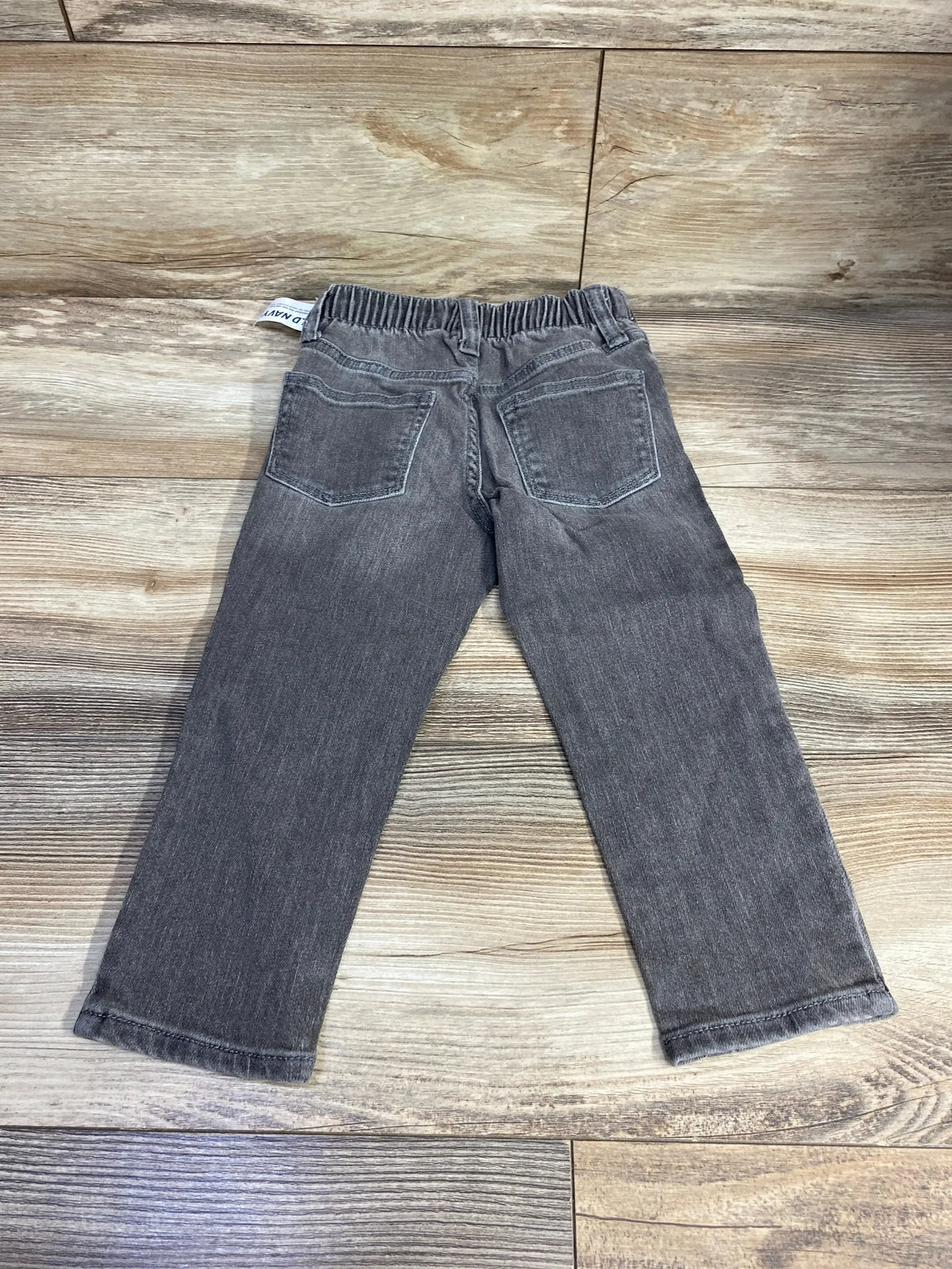 Gray toddler jeans with back pockets and elastic waistband on wood floor