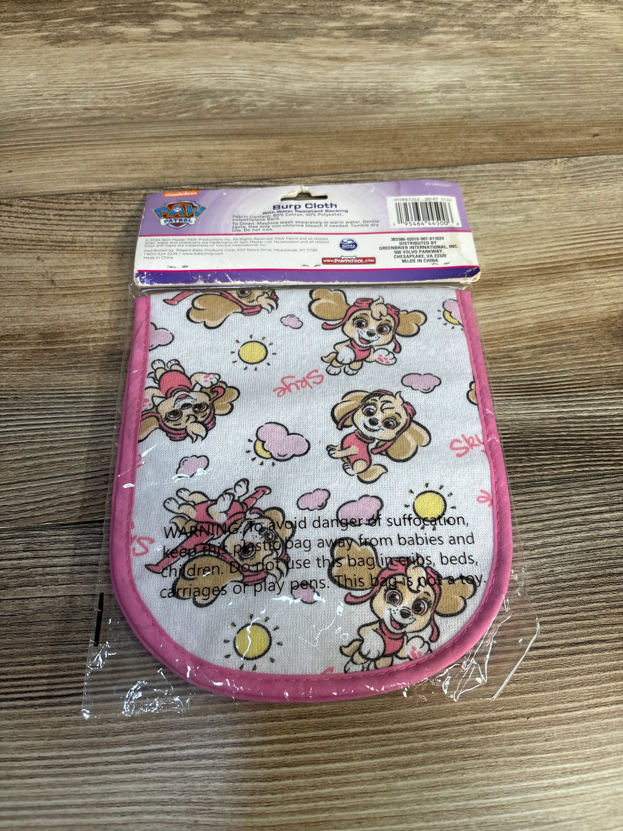 Paw Patrol Skye burp cloth with pink trim, cartoon dog print, on wooden surface