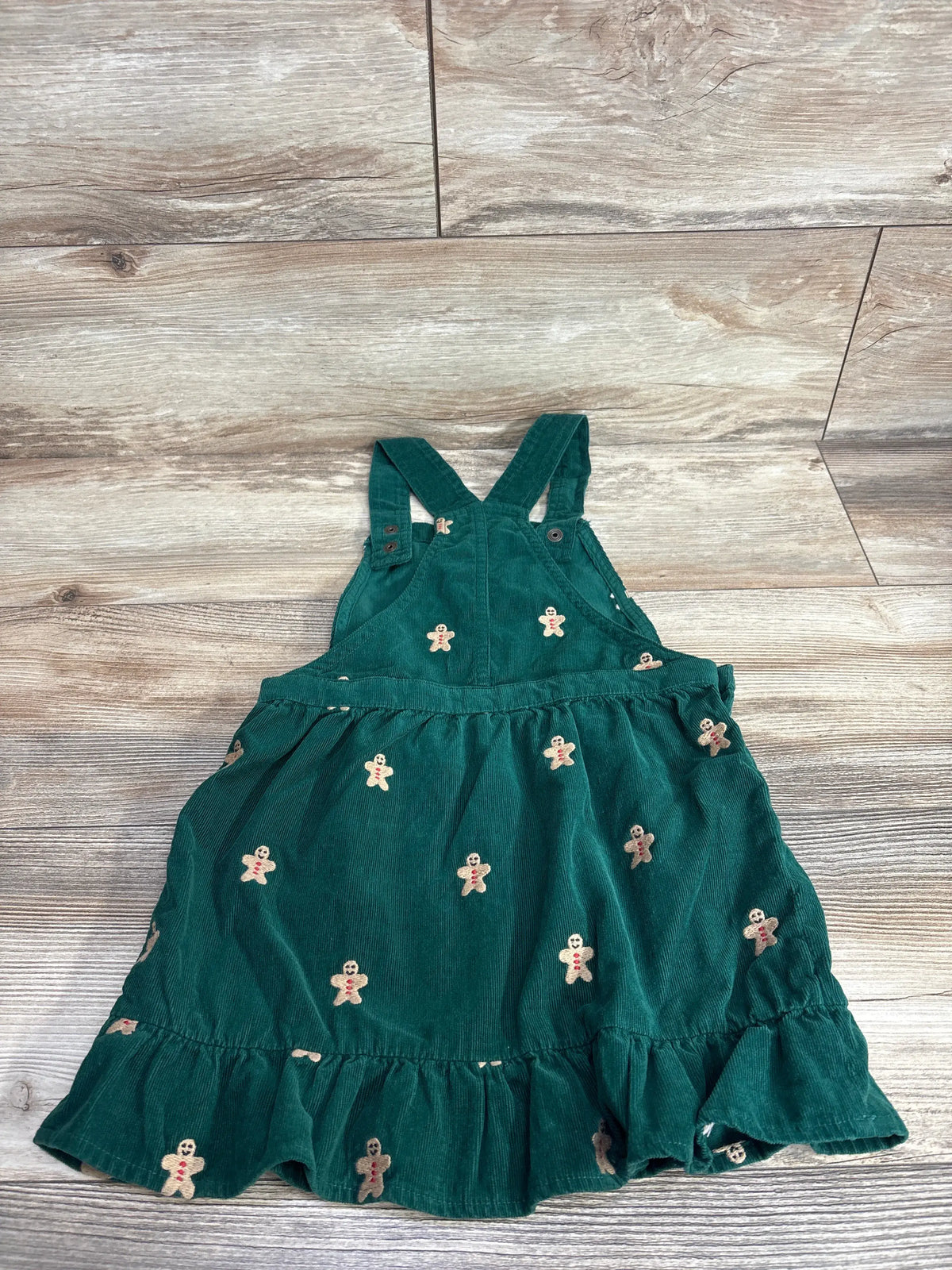 Green corduroy baby dress with gingerbread man print, ruffled hem, and adjustable straps for toddler girls.