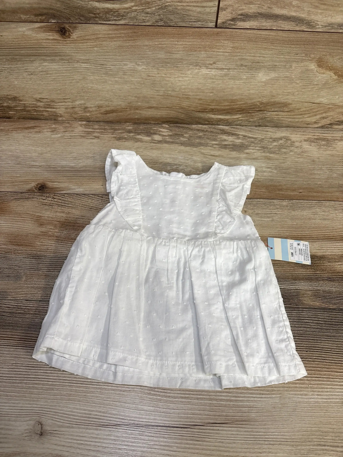 Front view of Cat and Jack white Swiss dot shirt showcasing flutter sleeves on a wood floor