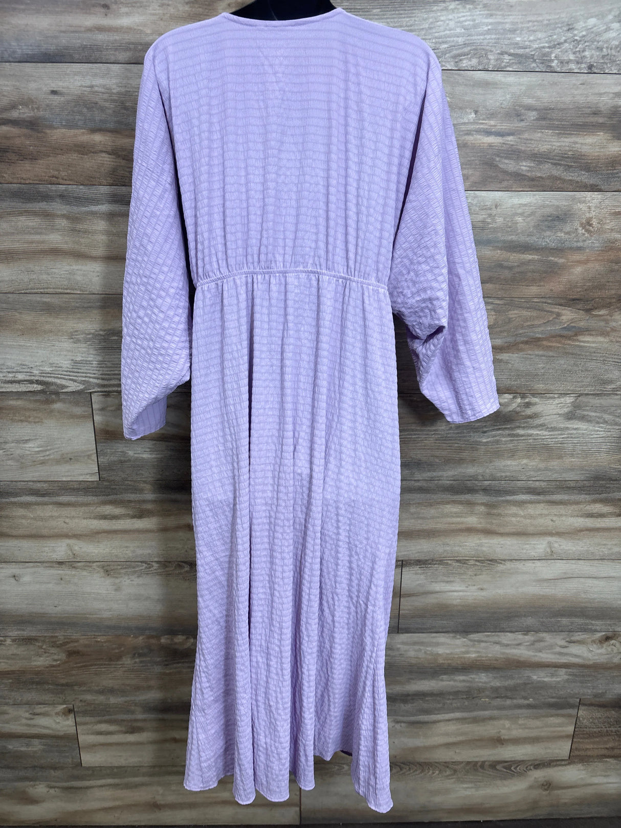 Lavender textured long-sleeve maxi dress displayed on mannequin against wood panel background