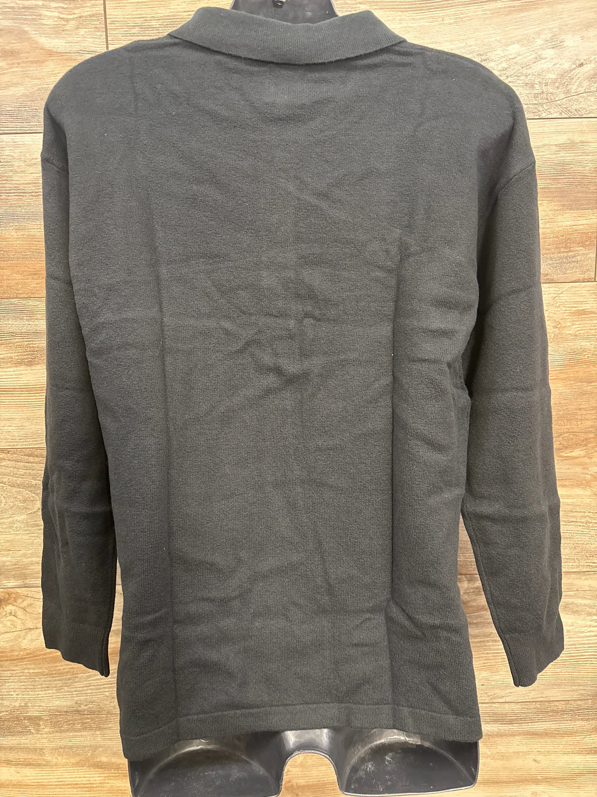 Dark gray long-sleeve knit sweater displayed on black mannequin against wooden floor background