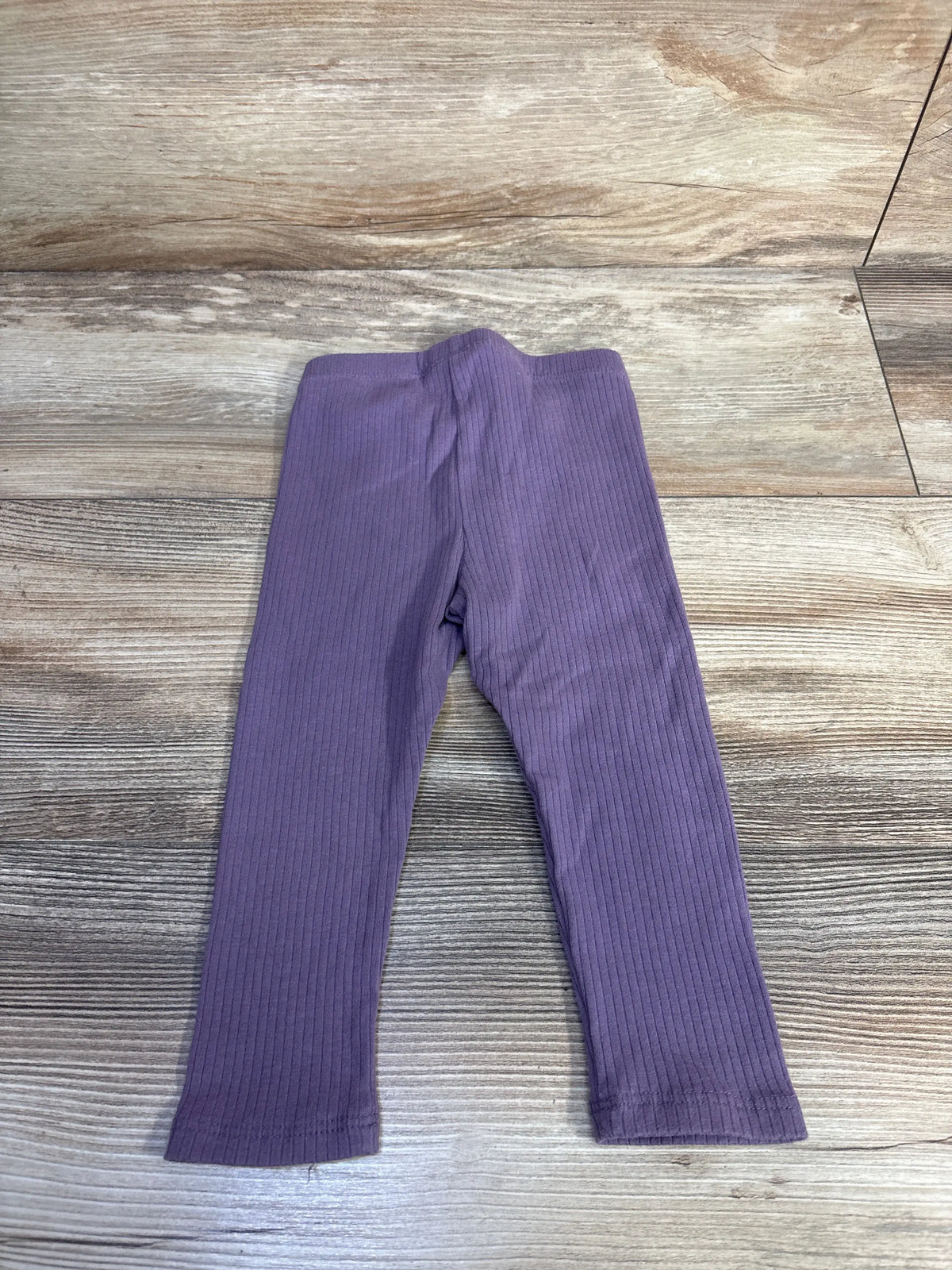 Front view of Cat & Jack purple ribbed leggings in size 18 months showcasing vertical ribbed texture on a wood grain background