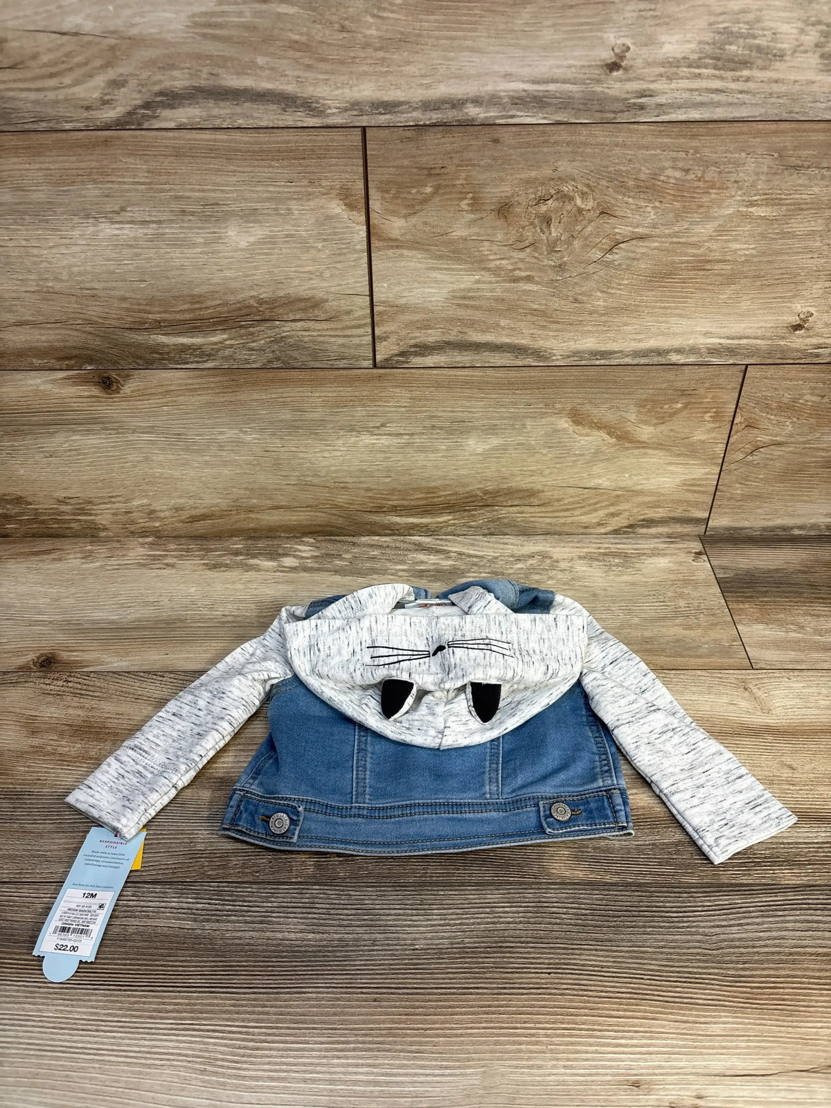 Baby denim jacket with gray sleeves and monster face hood, size 12 months, on wood floor