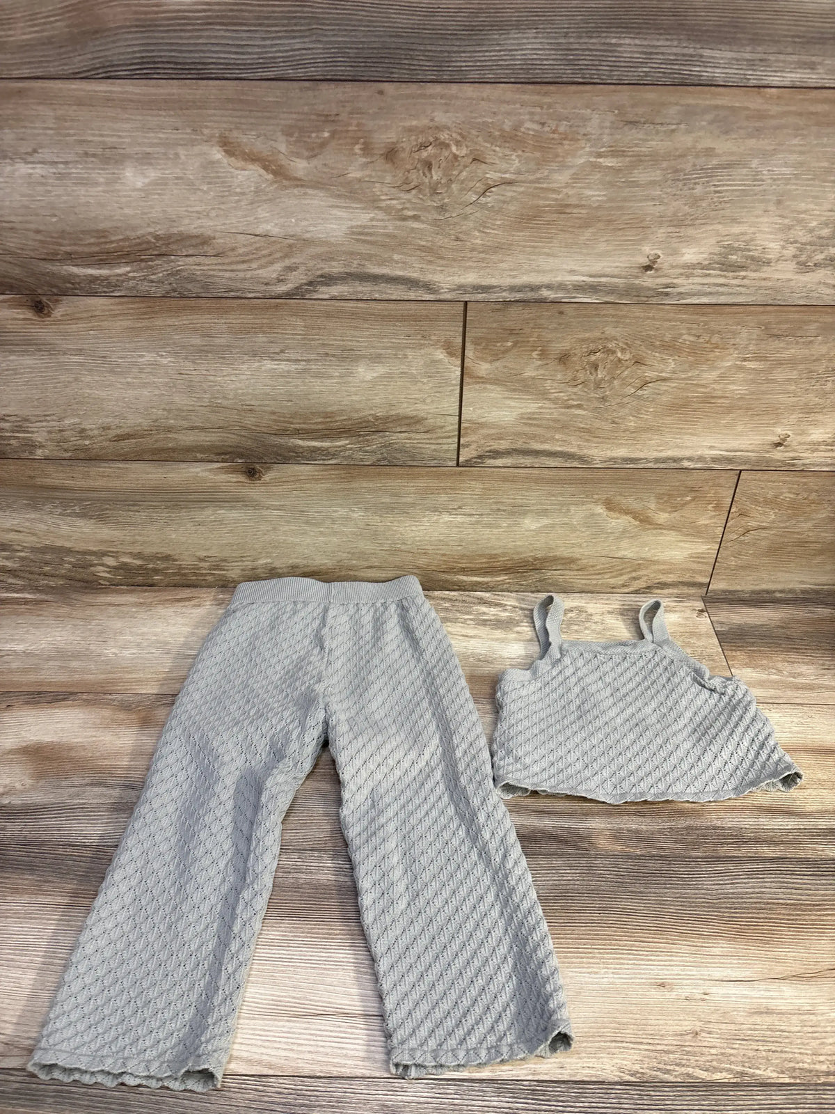 Top view of Rylee and Cru grey pointelle knit tank top and wide-leg pants set with scalloped edges on a wood floor