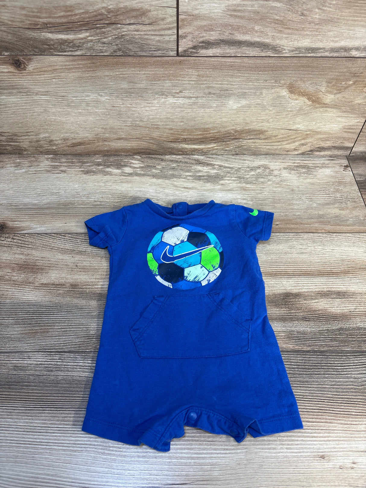 Blue baby romper with soccer ball graphic and short sleeves on wood background