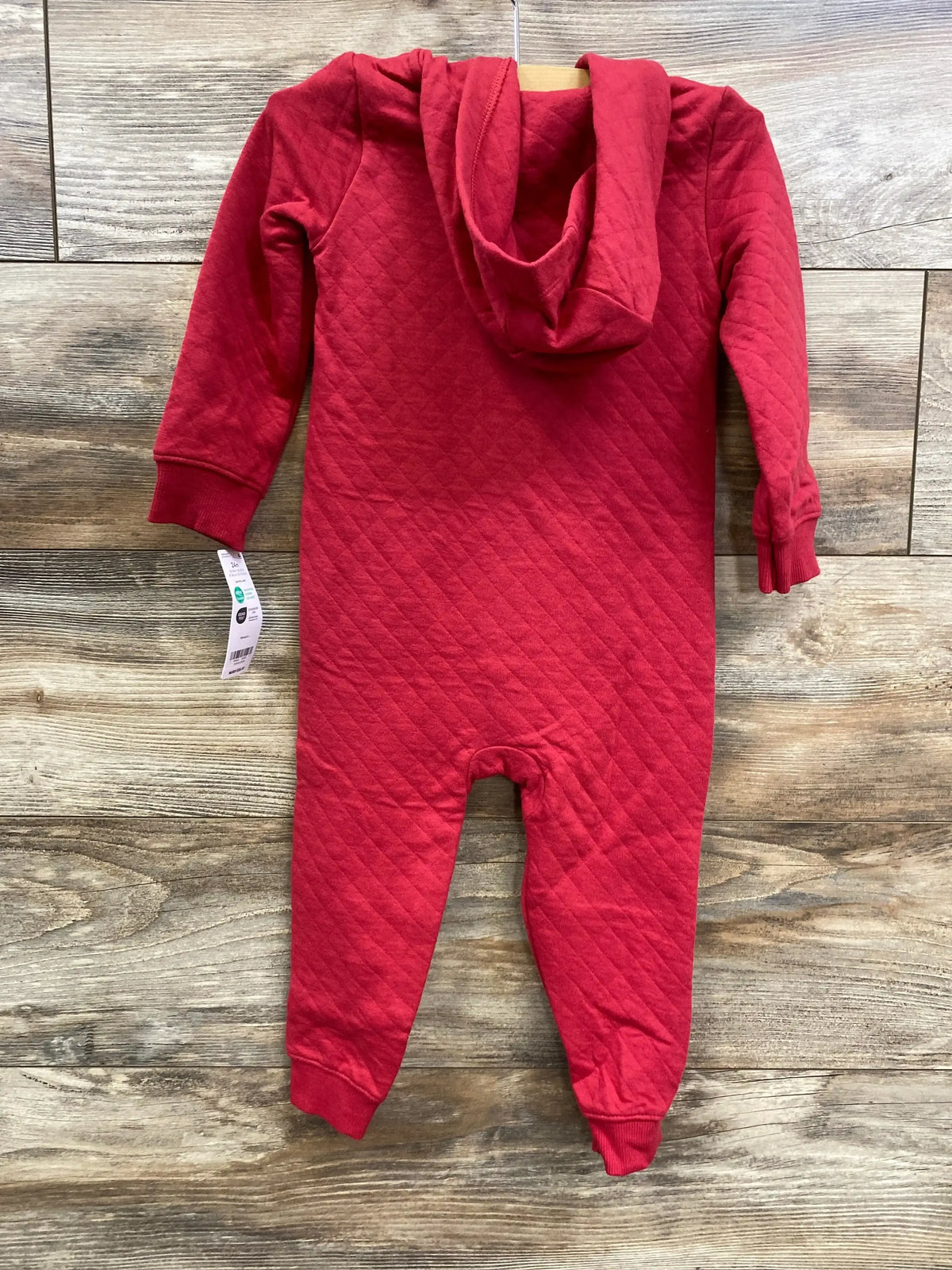 Red quilted hooded baby onesie hanging on wood wall with long sleeves and cuffs