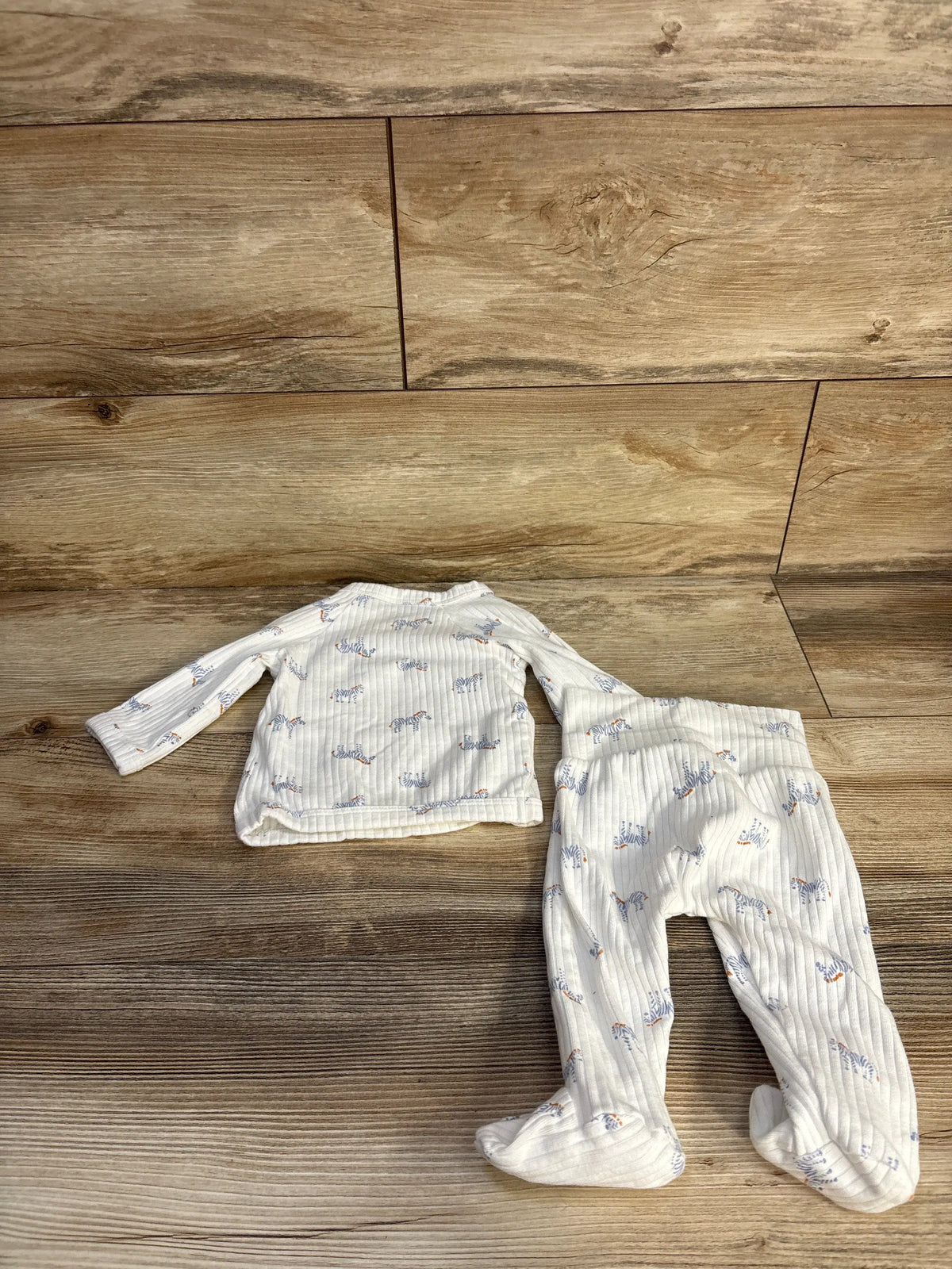 Top-down view of Just One You two-piece ribbed zebra kimono set showcasing footed bottoms on a wood floor