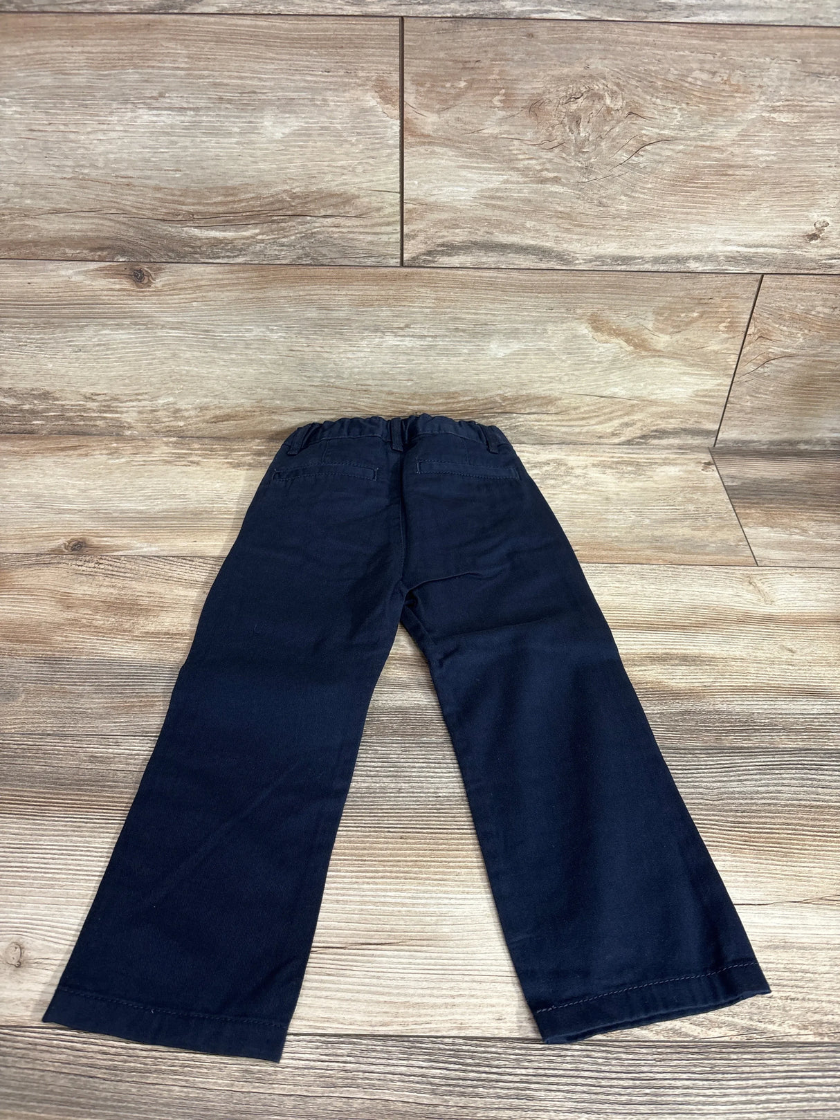 Back view of navy Children's Place 3T skinny chino pants showing elastic waist and back pockets on wood floor