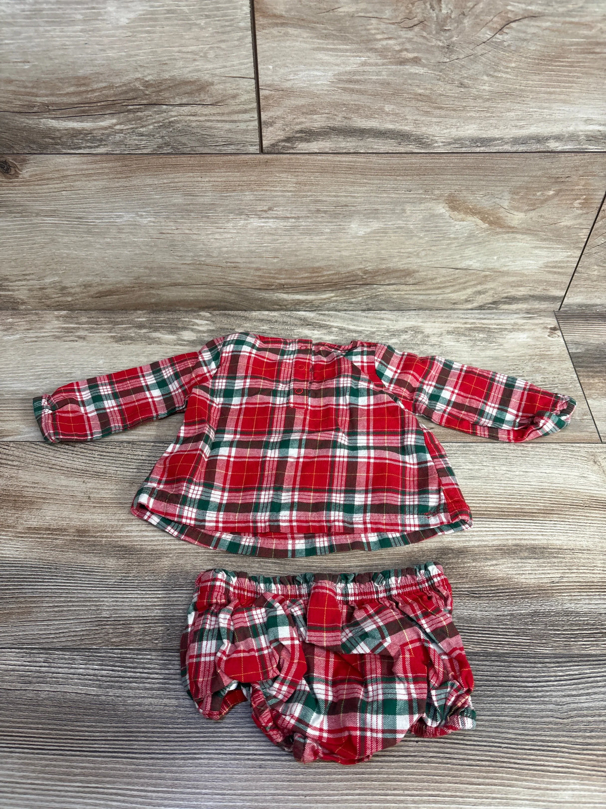 Red, green, and white plaid toddler long sleeve top and matching bloomers on wood background