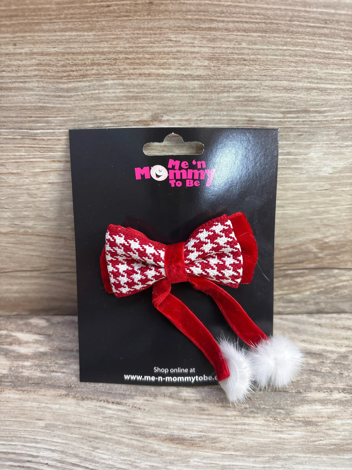 Red and white houndstooth baby bow with velvet tails and pom-poms on black card