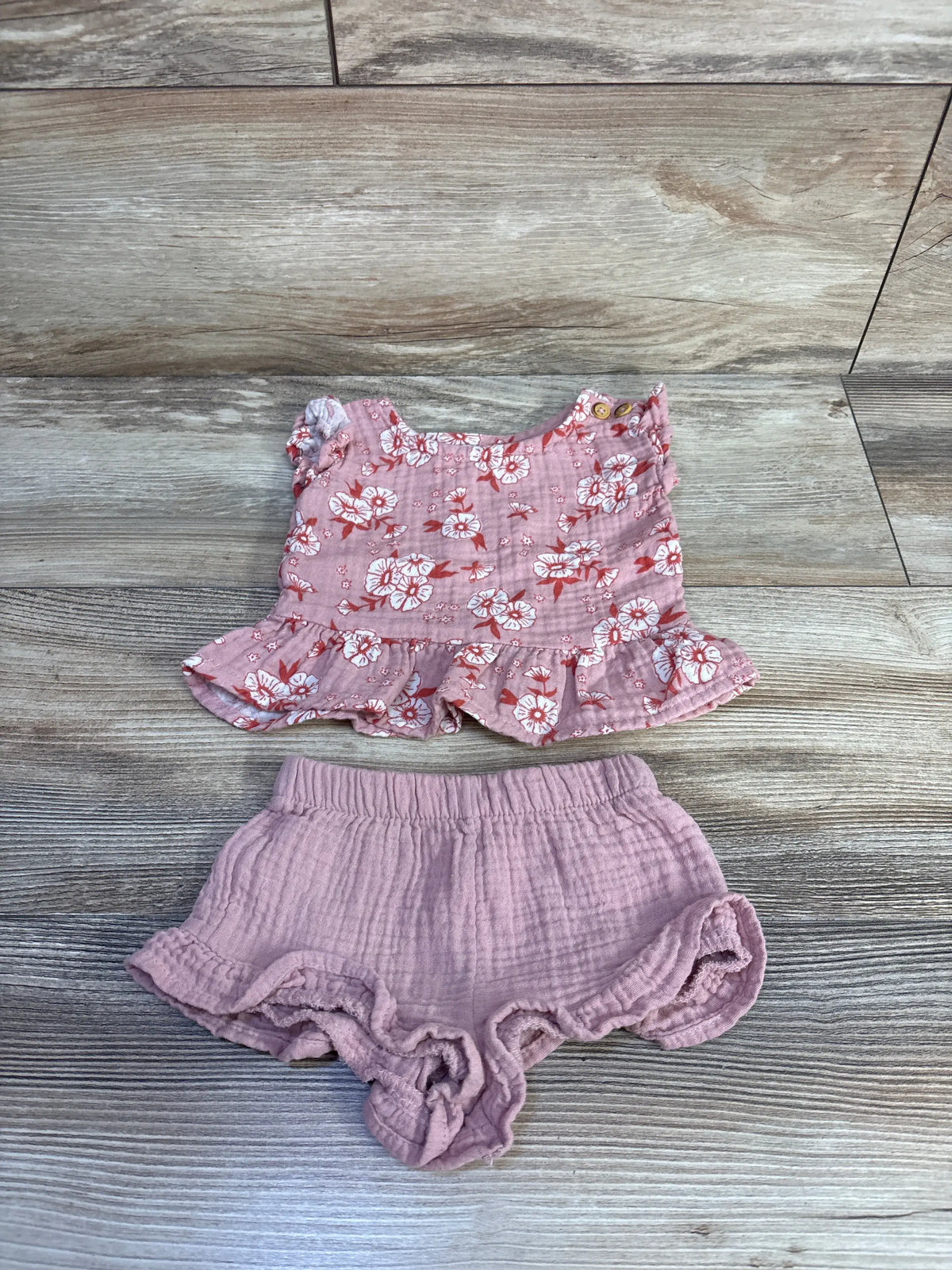 Top-down view of dusty rose Cat & Jack gauze peplum top and shorts set with floral print and ruffled hems on wood-grain background