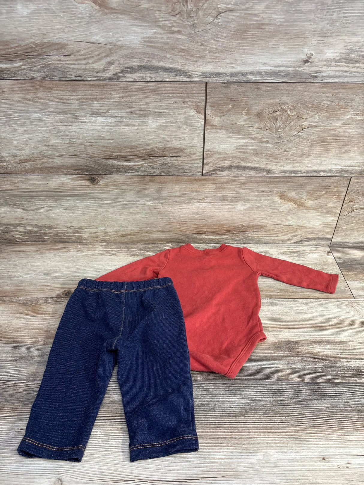 Flat lay of Pekkle 2-piece elephant-print set: rust long-sleeve bodysuit (back) and navy elastic-waist pants on wood