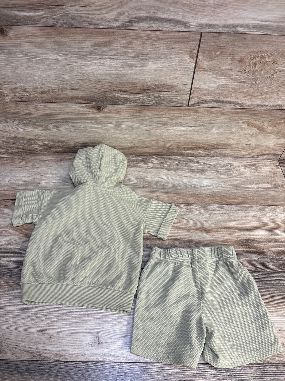 Soft mint green baby hoodie and shorts set on wood floor, cozy infant clothing