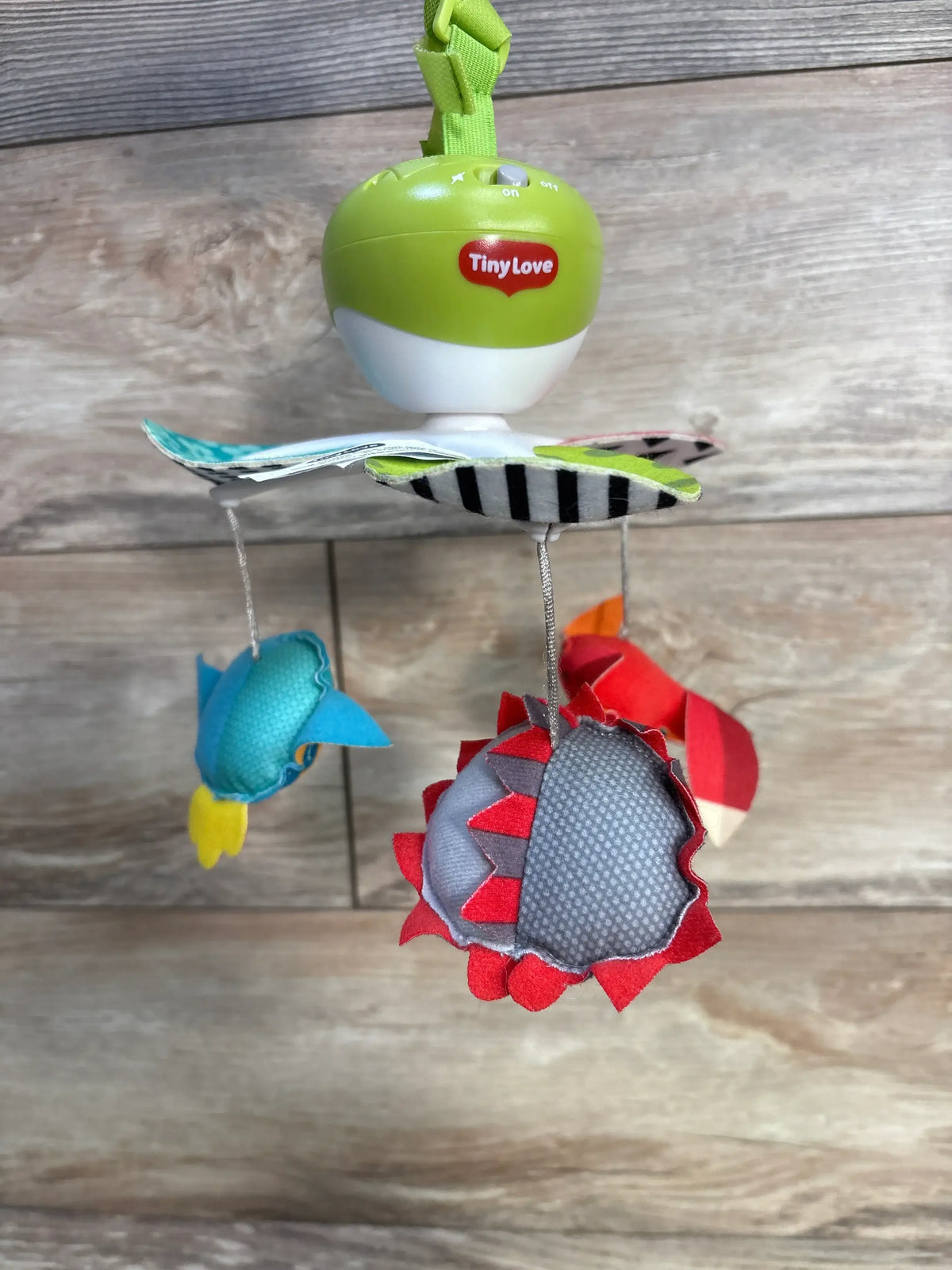 Front view of Tiny Love 3-in-1 Take Along Mobile showcasing colorful toys and high-contrast patterns on a wood background