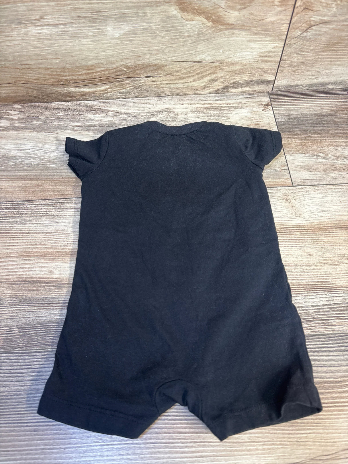 Black short sleeve baby romper on wood floor, children's clothing resale