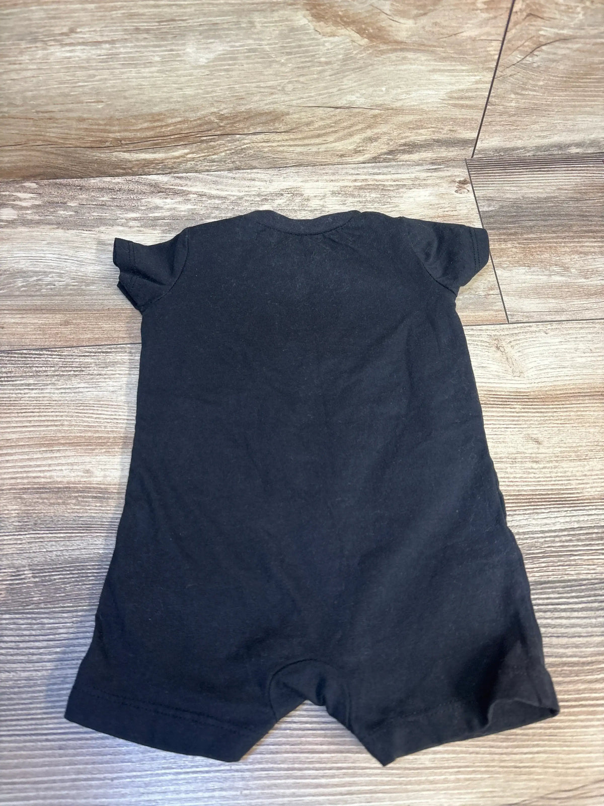 Black short sleeve baby romper on wood floor, children's clothing resale