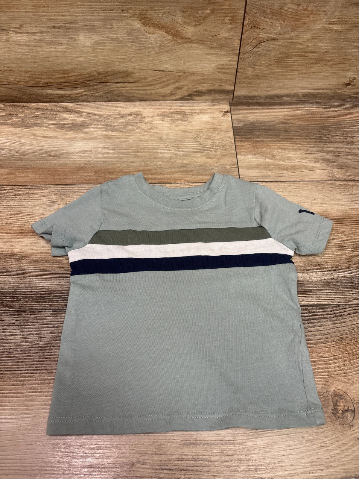 Front view of Lee green shirt in size 18 months showcasing horizontal olive, white, and navy stripes on a wooden background