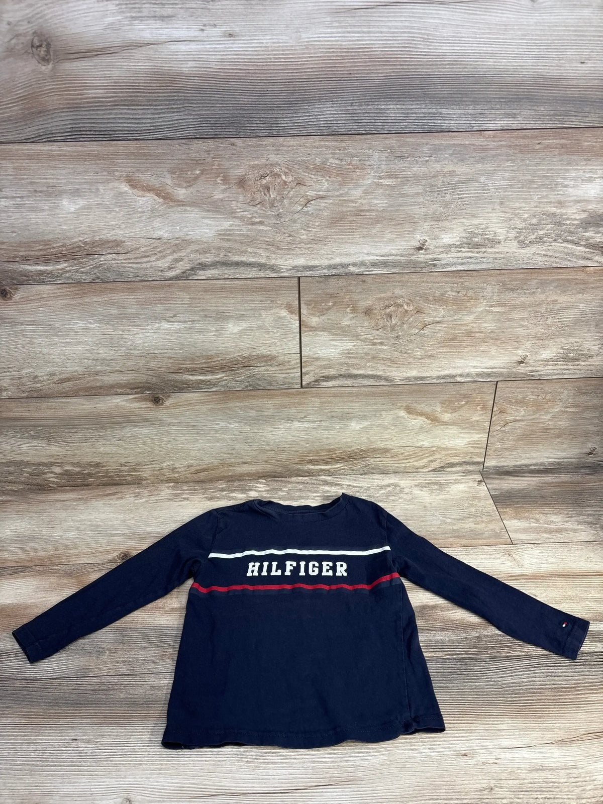 Navy blue long-sleeve Tommy Hilfiger shirt with white and red stripes on wood floor