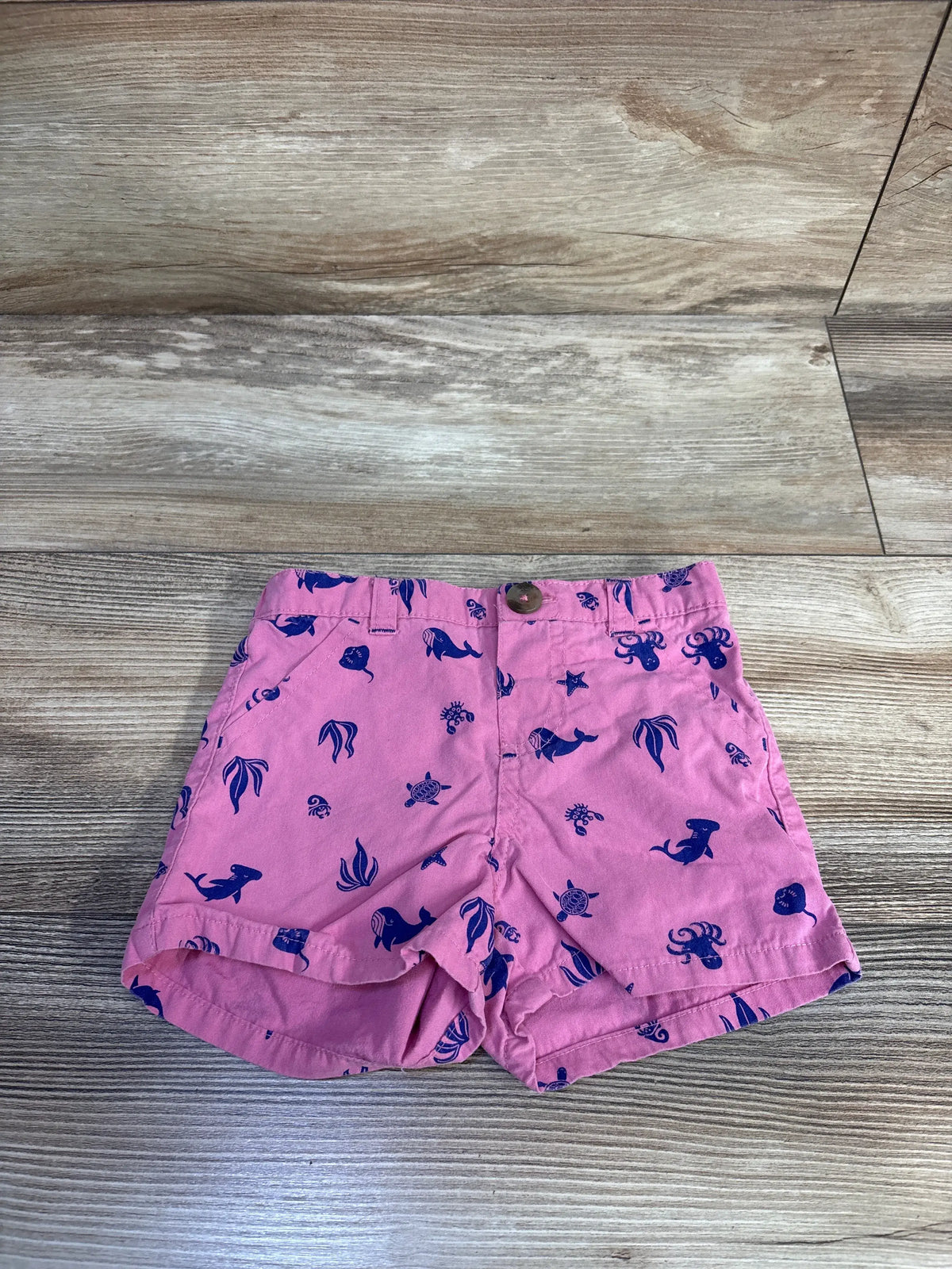 Pink Cat & Jack baby shorts with blue sea animal print on a wooden background