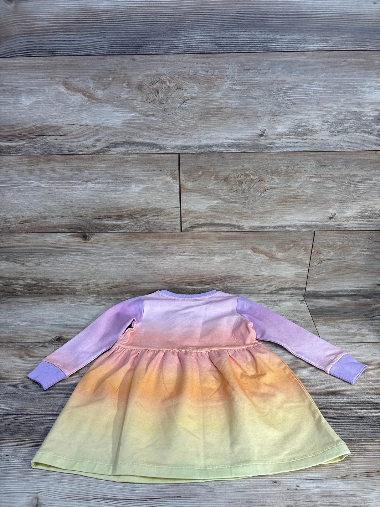 Pastel rainbow ombre long sleeve toddler dress on wood floor, kids clothing resale