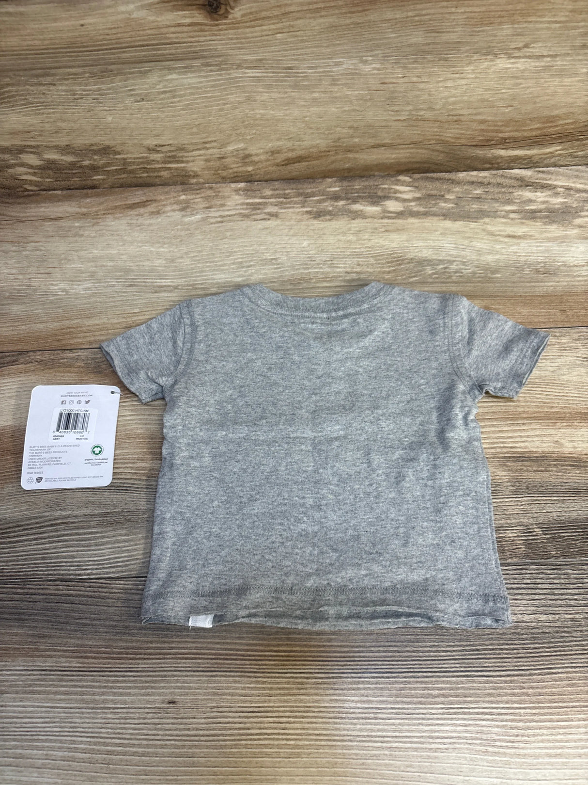 Back view of Burt's Bees Baby heather grey raw-hem short-sleeve shirt, size 3-6 months, tag visible on wood floor background