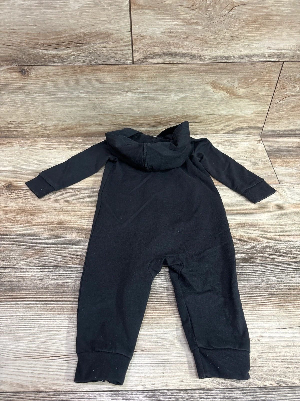 Black Nike hooded coverall for baby size 9m laid flat on a wooden background