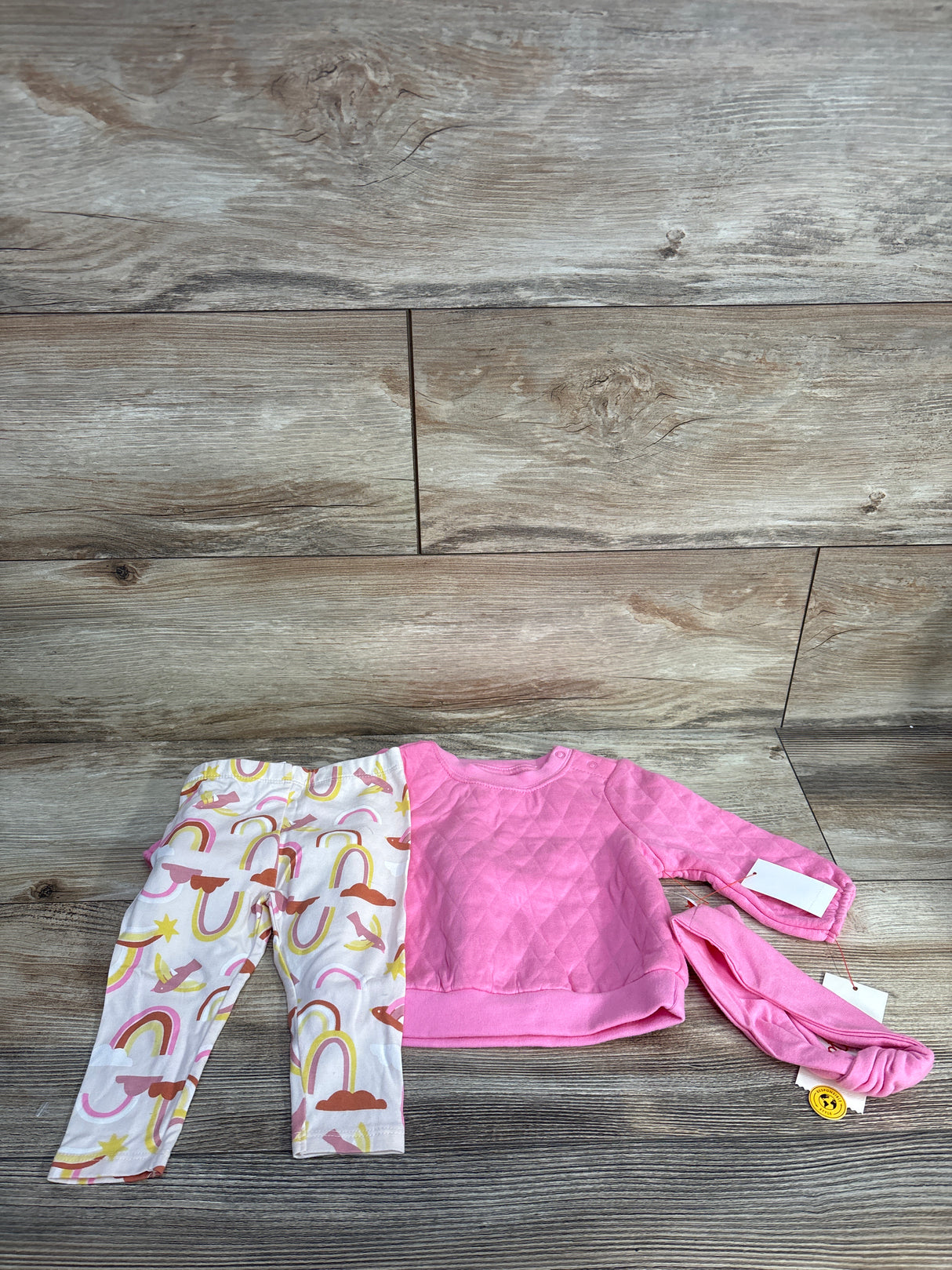 Baby outfit set with pink quilted long-sleeve top, rainbow print leggings, and matching pink headband
