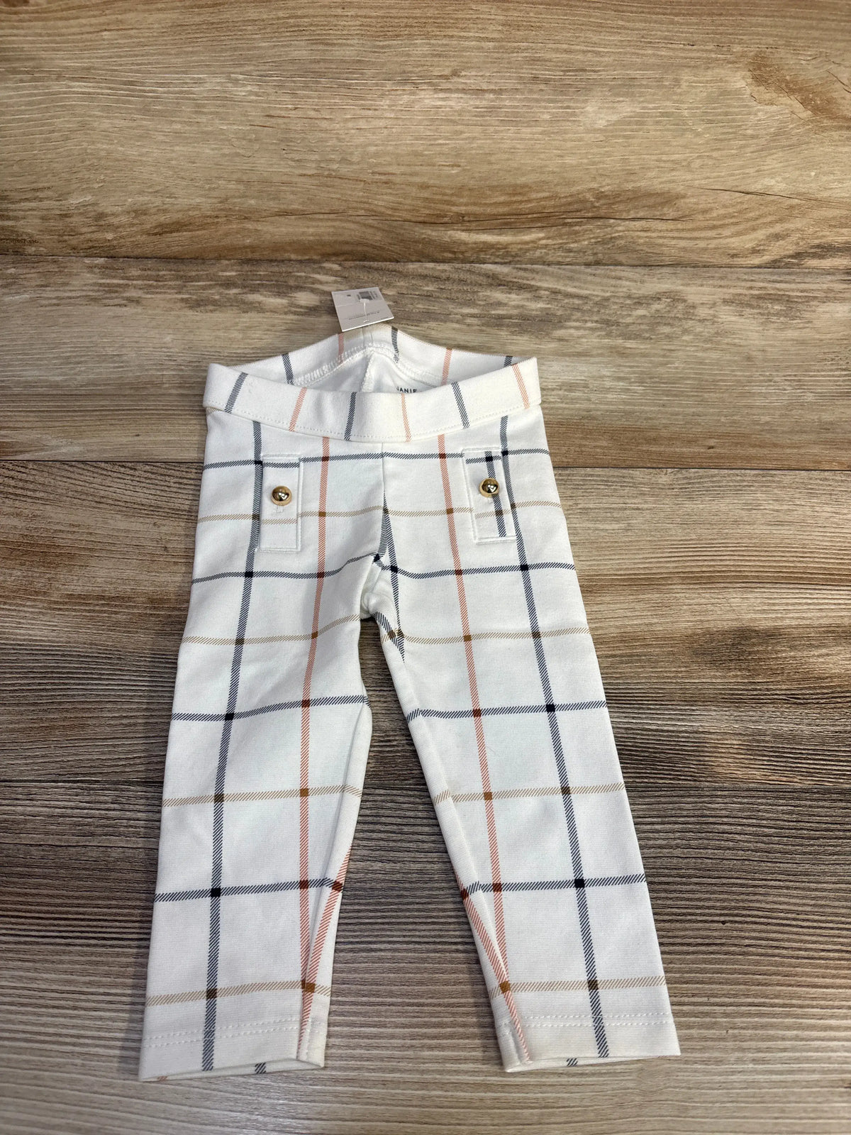 Front view of Janie & Jack Plait Button Ponte Pants showcasing ivory plaid and gold-tone button details on a wood background