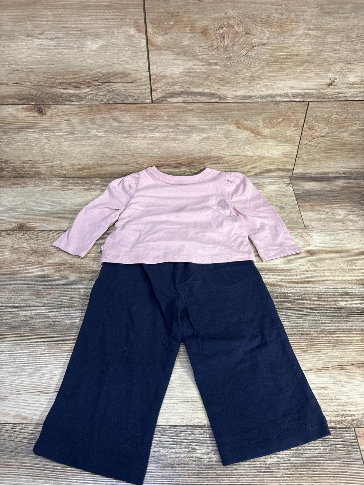 Front view of NEW Baby Gap 2pc Puff Sleeve Shirt and Pants Set showcasing pink puff sleeve shirt and navy pants on a wood floor