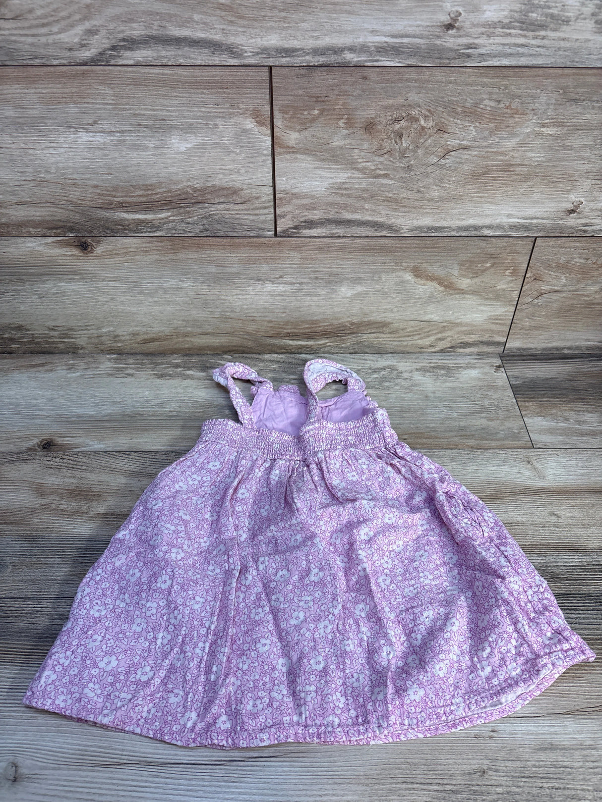 Flat lay of Cat & Jack pink floral tank dress size 3T showcasing smocked bodice and thin shoulder straps on light wood background
