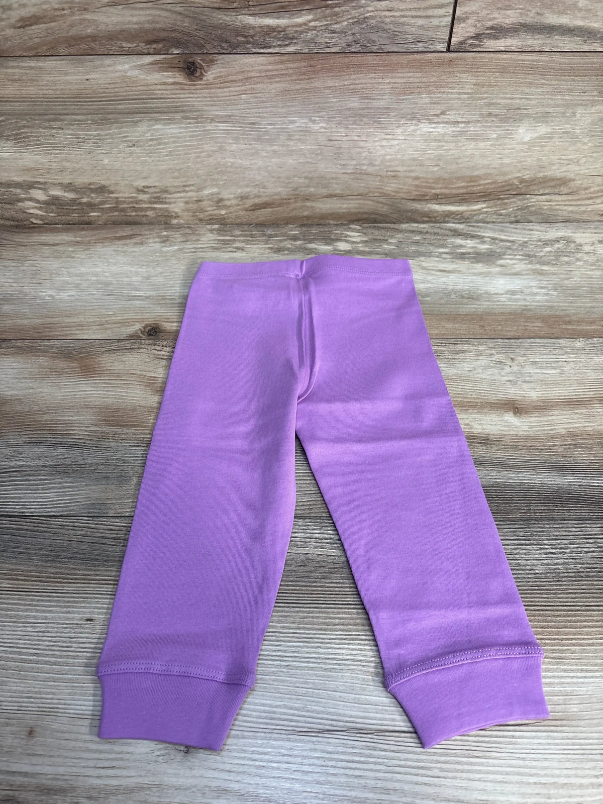 Light purple baby leggings on wooden floor, soft cotton pants, infant clothing