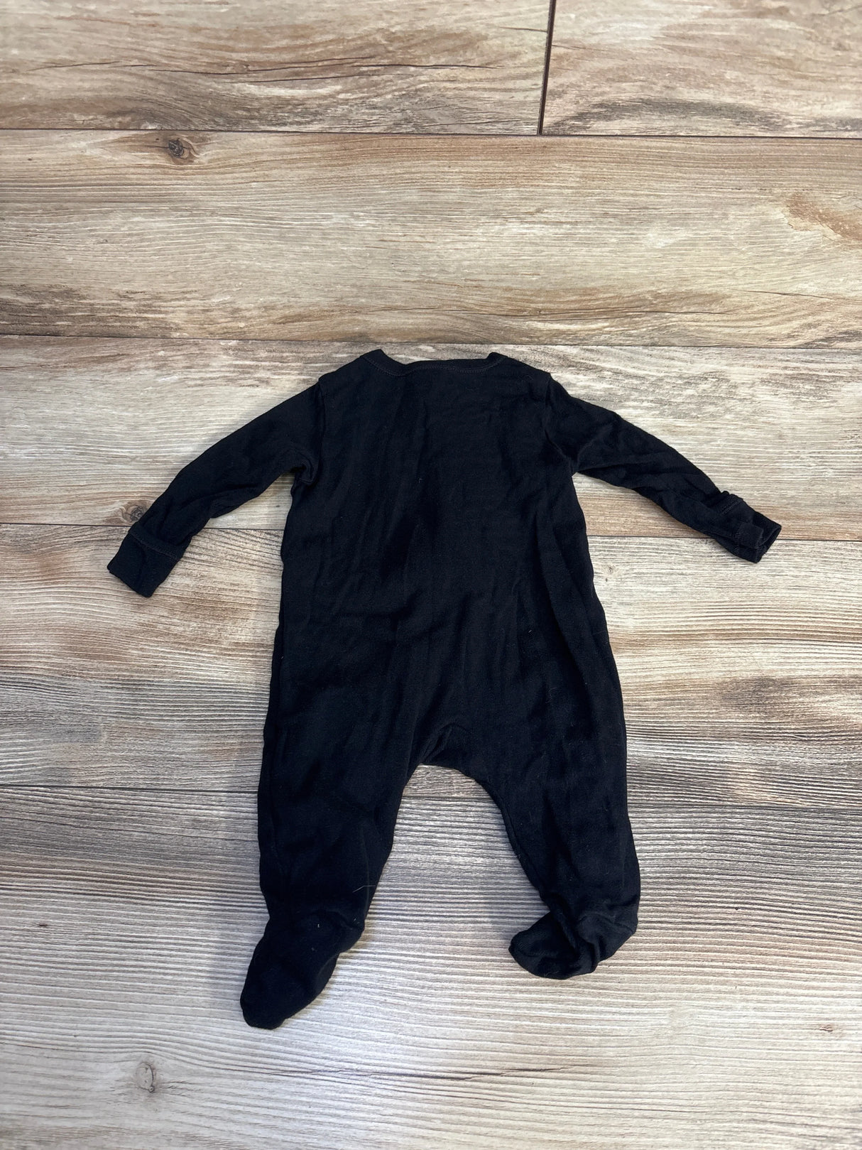 Black baby onesie laid flat on wooden floor, ideal for infant clothing resale