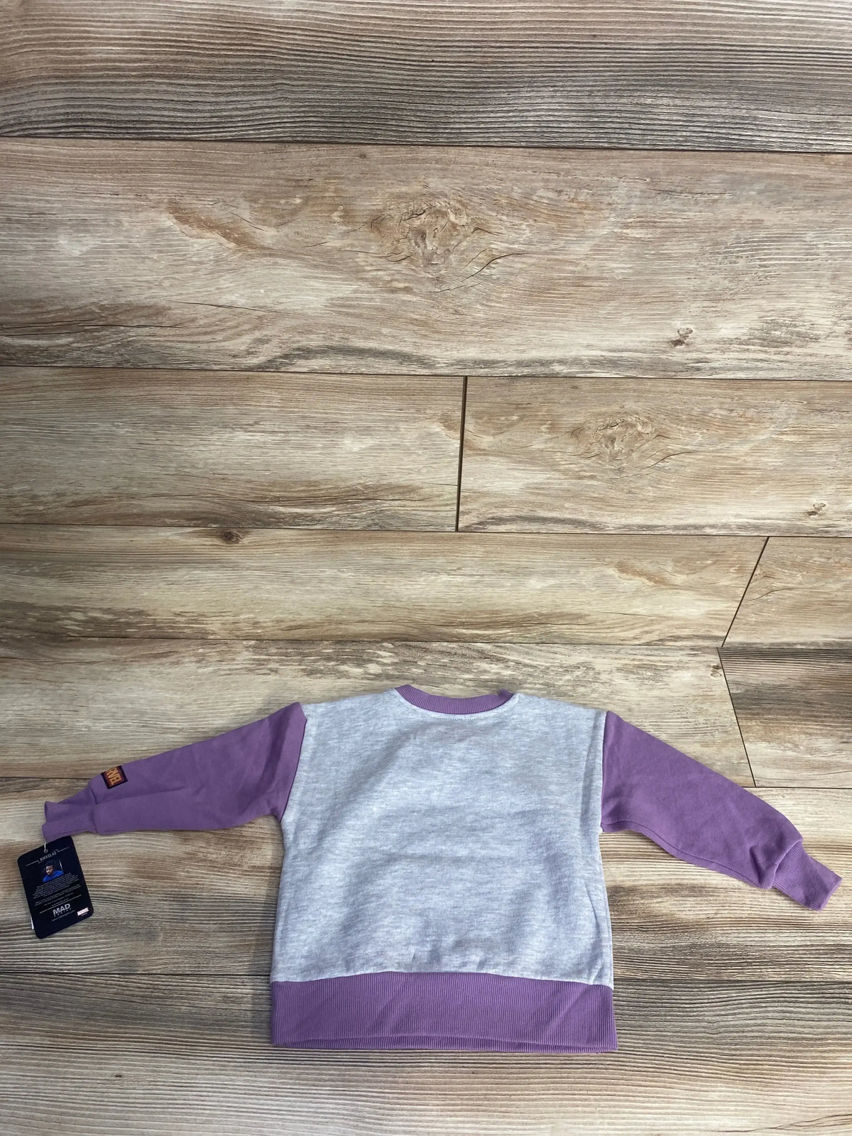 Back view of Marvel Black Panther raglan toddler sweatshirt showing gray body, lilac sleeves and hem on wooden floor
