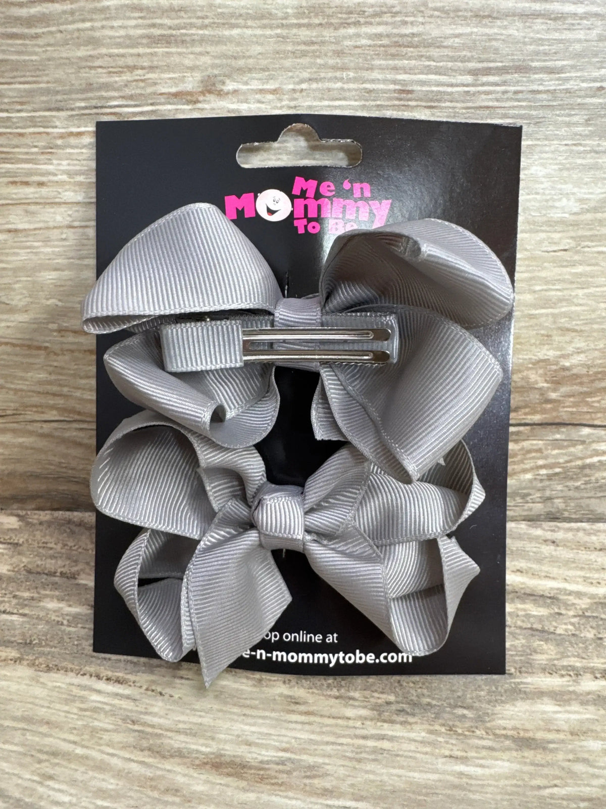 Front view of NEW Medium Hair Bows Grey 2pk showcasing grosgrain ribbon bows on alligator clips and Me n Mommy To Be branded card on wood plank background