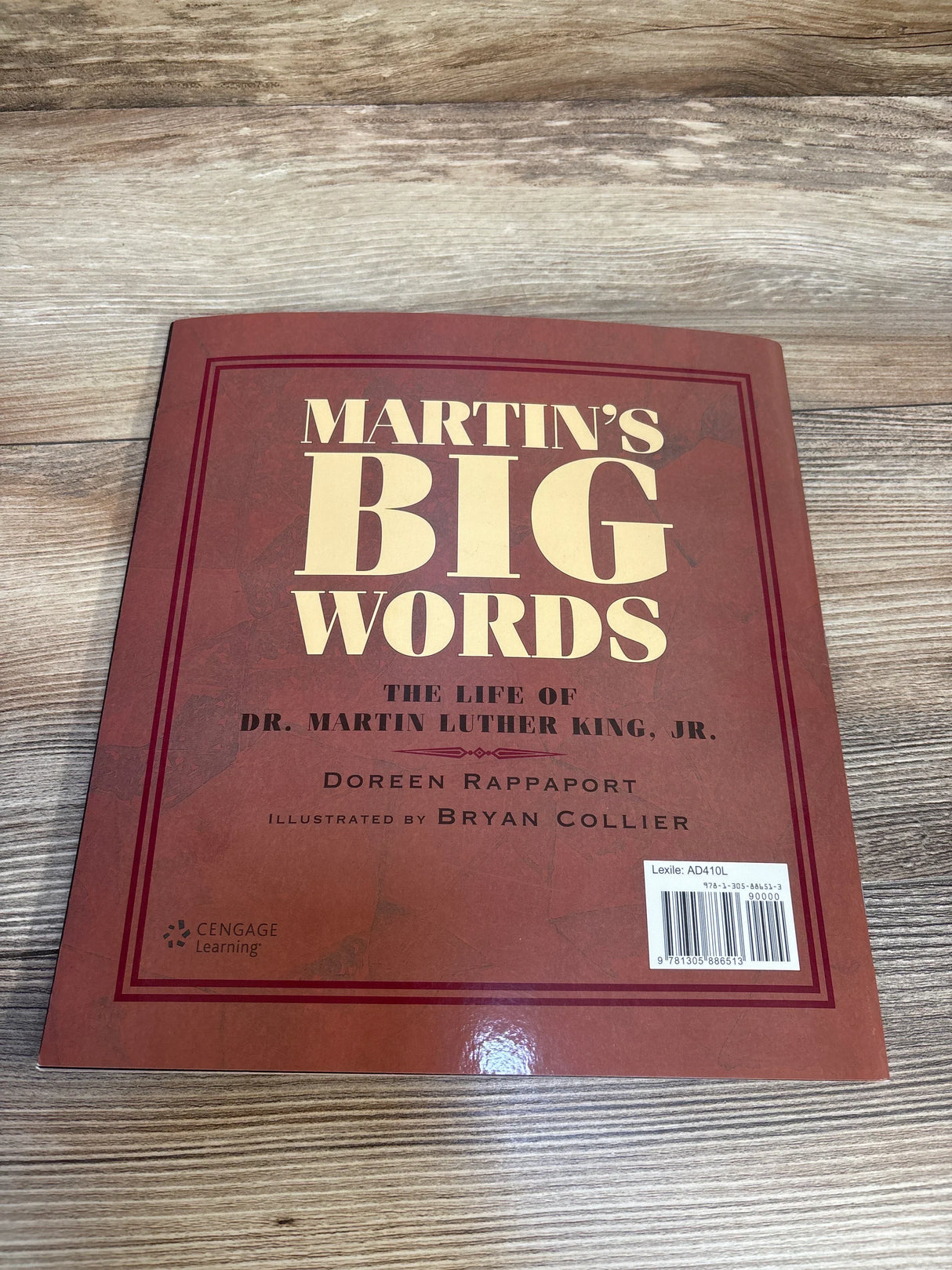 Top-down view of Martin’s Big Words paperback showing front cover with large title text, author name, and barcode on wooden surface